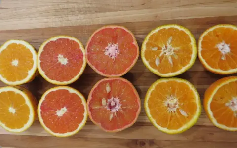 Mitades de naranjas y toronjas en una tabla de madera. La naranja sirve para aportar vitamina C y un sabor refrescante a tus comidas.