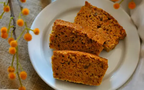 Rebanadas de bizcocho de zanahoria saludable, con trocitos de zanahoria visibles, servidas en un plato blanco.