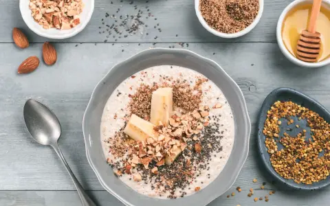 Un tazón de avena con plátano, almendras picadas, semillas de chía y miel. ¡Así es que es la avena, un desayuno nutritivo!