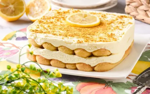 Delicioso tiramisú de limón en capas, adornado con galletas y una rodaja de limón.