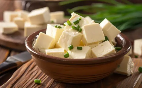 Tofu cortado en cubos, listo para aprender como cocinar tofu. Decorado con cebollín verde.