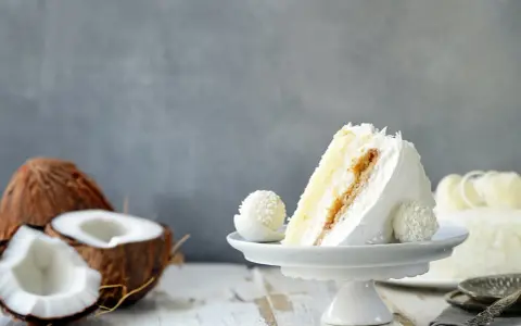Deliciosa tarta de coco, ideal para tus recetas con harina de coco. Un trozo cremoso con coco rallado y un bombón a juego.