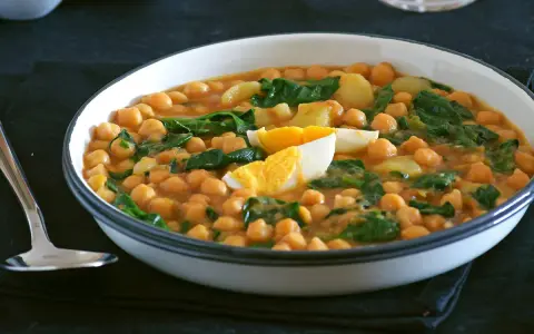 Plato humeante de garbanzos con espinacas y huevo duro, una deliciosa receta de garbanzos tradicional.