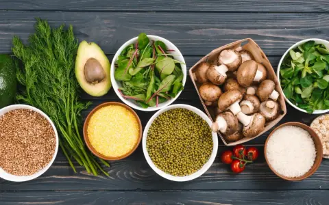 Variedad de alimentos ricos en proteinas vegetales: aguacate, hinojo, lentejas, champiñones, arroz, tomates y hojas verdes.