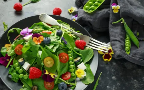 Ensalada vibrante con frambuesas, arándanos, guisantes y flores comestibles, celebrando las frutas de primavera.
