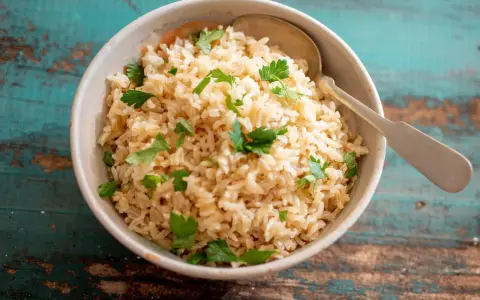 Un tazón de arroz integral esponjoso, adornado con perejil fresco, listo para ser disfrutado.