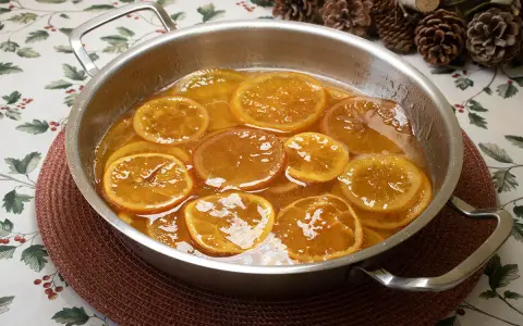 Rodajas de naranjas naturales confitadas en almíbar, un delicioso postre listo para disfrutar.