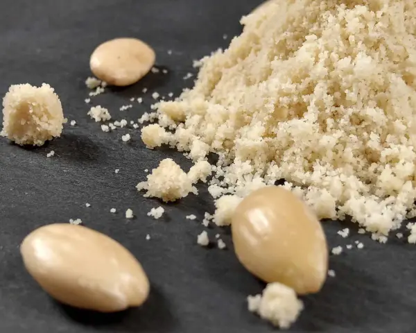Montón de harina de almendras y almendras enteras. Aprende como hacer harina de almendras casera.