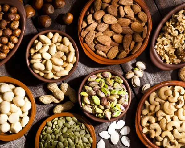 Variedad de frutos secos en cuencos: almendras, nueces, pistachos, anacardos, cacahuetes, avellanas y semillas de calabaza. ¡Perfectos para activar frutos secos!