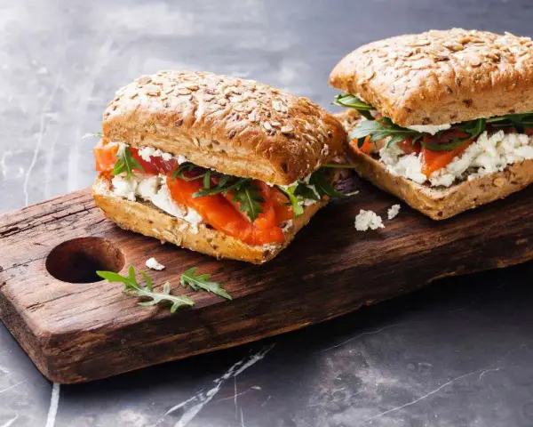 Dos sándwiches de salmón y queso fresco en pan integral, perfectos para un menú de ayuno intermitente.