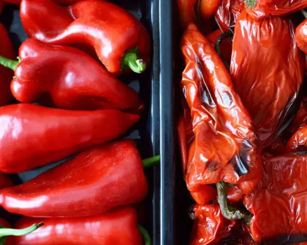 Dos recipientes llenos de pimientos rojos, unos frescos y brillantes, otros pimientos asados con la piel arrugada y un toque tostado.
