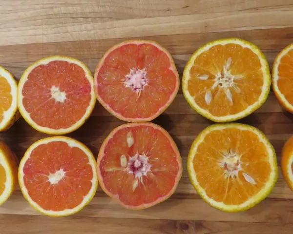 Mitades de naranjas y toronjas en una tabla de madera. La naranja sirve para aportar vitamina C y un sabor refrescante a tus comidas.