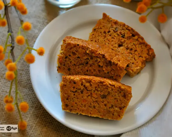 Rebanadas de bizcocho de zanahoria saludable, con trocitos de zanahoria visibles, servidas en un plato blanco.