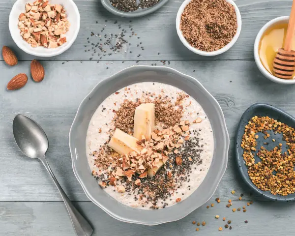 Un tazón de avena con plátano, almendras picadas, semillas de chía y miel. ¡Así es que es la avena, un desayuno nutritivo!