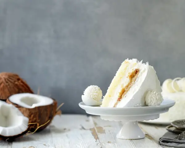 Deliciosa tarta de coco, ideal para tus recetas con harina de coco. Un trozo cremoso con coco rallado y un bombón a juego.