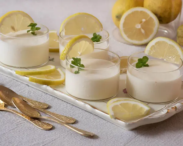 Delicioso postre de lemon curd receta original, servido en vasos con rodajas de limón y menta.