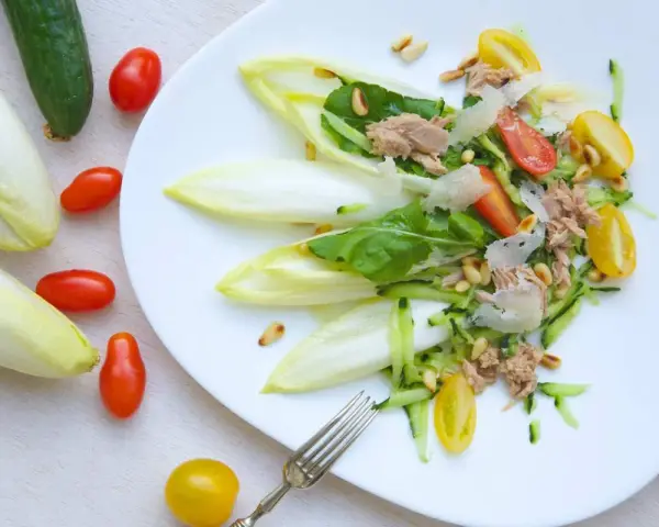 Ensalada de endivias con atún, tomate, pepino y piñones. Fresca y ligera, perfecta para un día soleado.