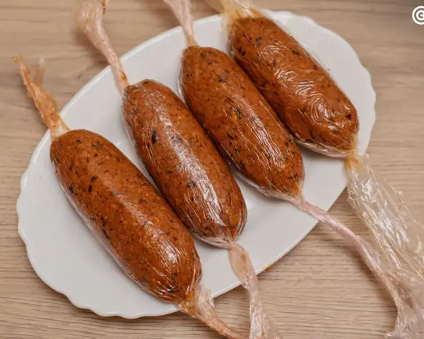 Cuatro chorizos veganos envueltos en plástico transparente, listos para cocinar.