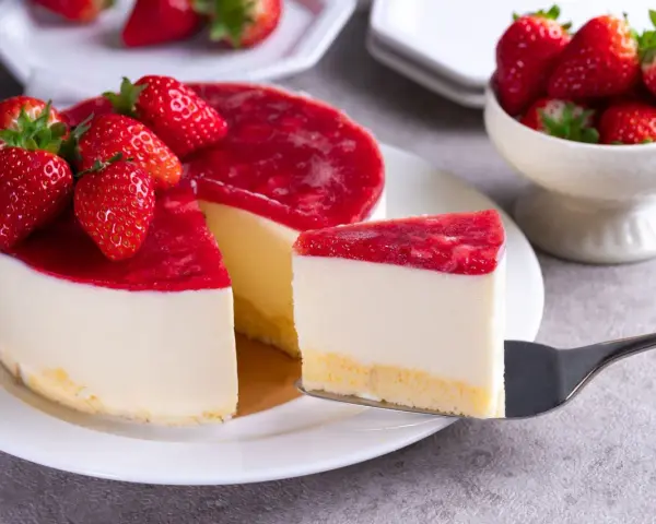 Deliciosa tarta de queso con frutos rojos, cubierta con una capa brillante de mermelada de fresa y decorada con fresas frescas.
