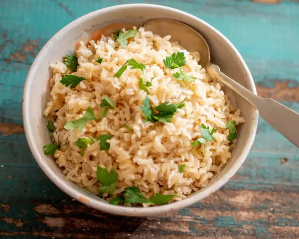 Un tazón de arroz integral esponjoso, adornado con perejil fresco, listo para ser disfrutado.