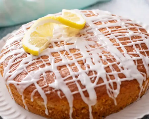 Pastel redondo con glaseado de limón y rodajas de limón fresco.