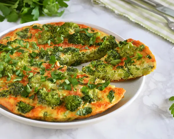 Deliciosa tortilla de brócoli, recién hecha y espolvoreada con perejil fresco. Un plato saludable y sabroso.