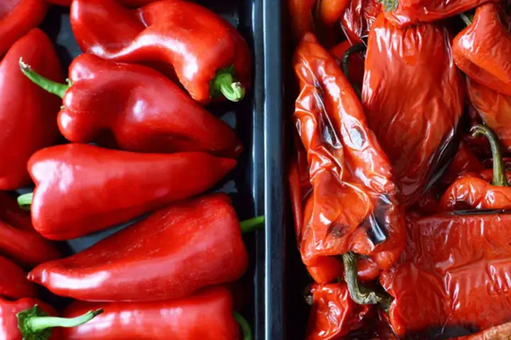 Dos recipientes llenos de pimientos rojos, unos frescos y brillantes, otros pimientos asados con la piel arrugada y un toque tostado.