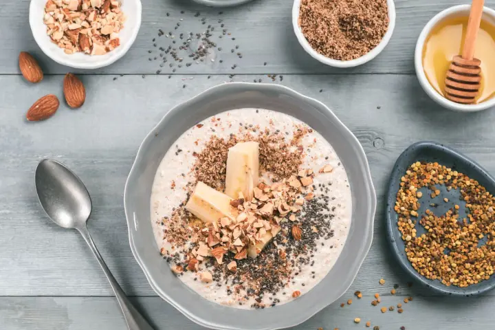 Un tazón de avena con plátano, almendras picadas, semillas de chía y miel. ¡Así es que es la avena, un desayuno nutritivo!