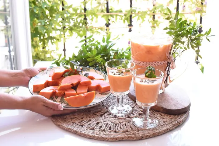 Delicioso zumo de papaya servido en copas y jarra, acompañado de papaya fresca en rodajas.