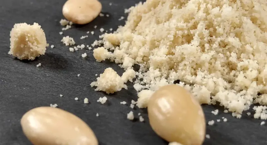 Montón de harina de almendras y almendras enteras. Aprende como hacer harina de almendras casera.