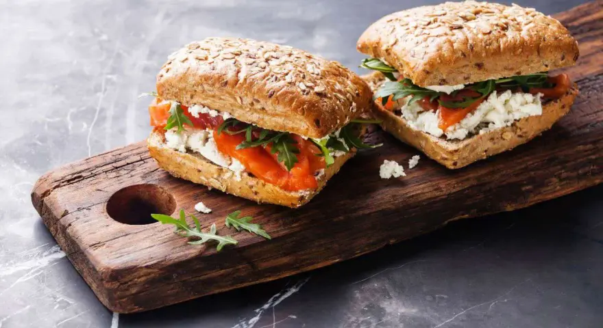 Dos sándwiches de salmón y queso fresco en pan integral, perfectos para un menú de ayuno intermitente.