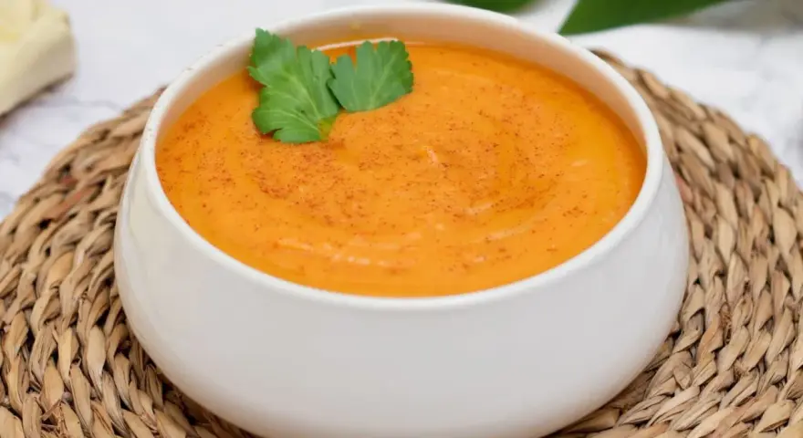 Crema de batata cremosa y reconfortante, espolvoreada con pimentón y decorada con perejil fresco.