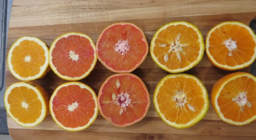 Mitades de naranjas y toronjas en una tabla de madera. La naranja sirve para aportar vitamina C y un sabor refrescante a tus comidas.