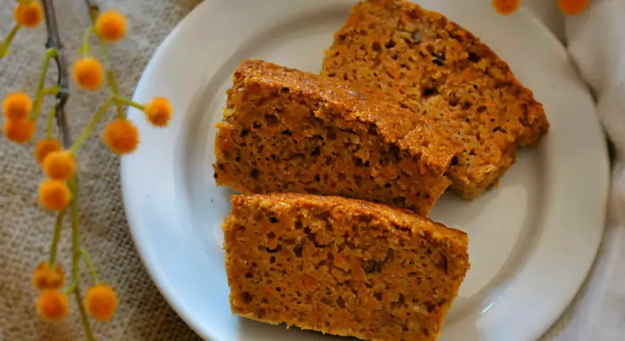 Rebanadas de bizcocho de zanahoria saludable, con trocitos de zanahoria visibles, servidas en un plato blanco.