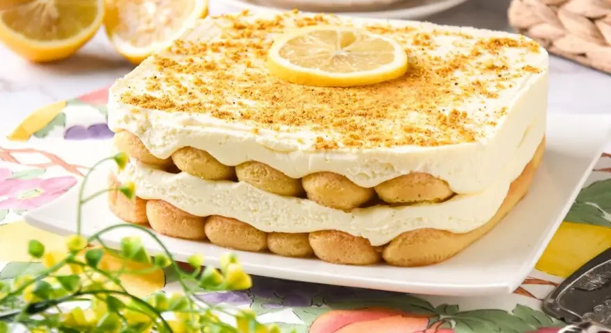 Delicioso tiramisú de limón en capas, adornado con galletas y una rodaja de limón.