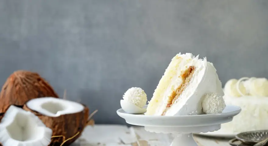 Deliciosa tarta de coco, ideal para tus recetas con harina de coco. Un trozo cremoso con coco rallado y un bombón a juego.