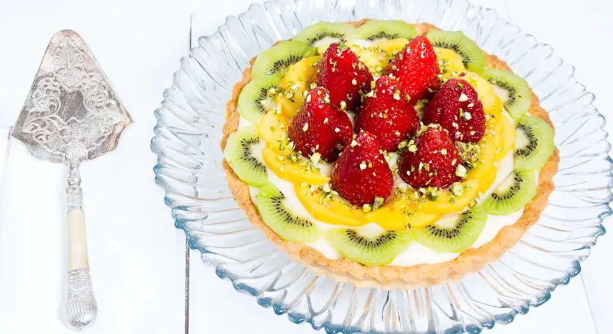 Tarta de frutas con fresas, kiwi y mango, decorada con pistachos. ¡Una delicia visual y gustativa!