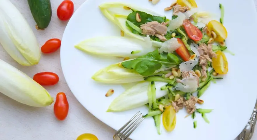 Ensalada de endivias con atún, tomate, pepino y piñones. Fresca y ligera, perfecta para un día soleado.