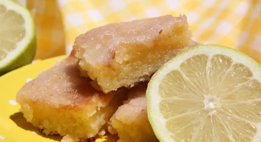 Deliciosos trozos de brownie de limón con glaseado brillante y rodajas de limón fresco.