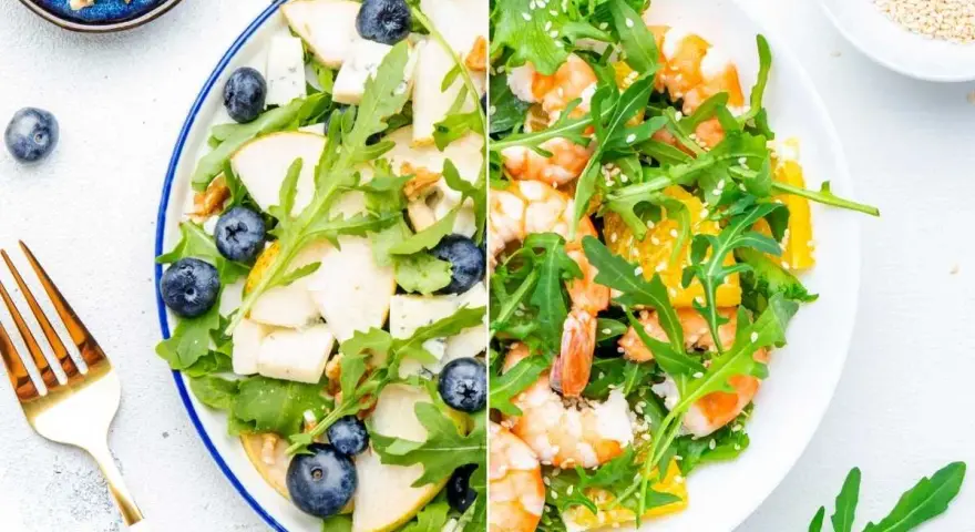 Dos ensaladas de rucula: una con pera, arándanos y nueces; la otra con gambas y naranja.