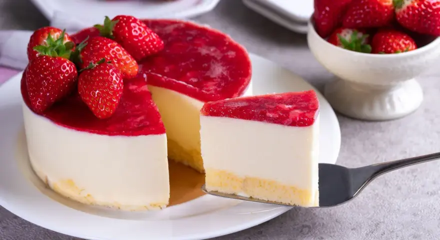 Deliciosa tarta de queso con frutos rojos, cubierta con una capa brillante de mermelada de fresa y decorada con fresas frescas.
