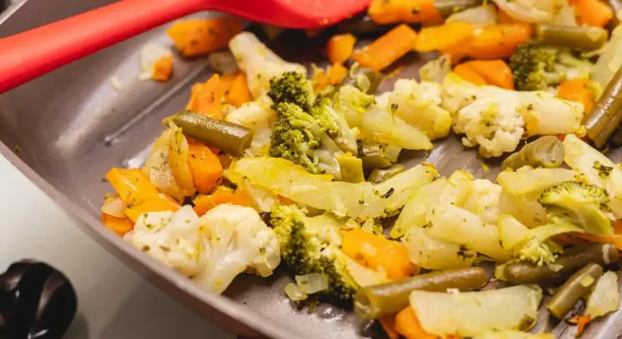 Coliflor al ajillo salteada con brócoli, zanahoria y judías verdes en una sartén, lista para servir.