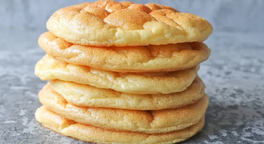 Una pila de pan nube, esponjosos y dorados, parecen nubes comestibles listas para ser disfrutadas.