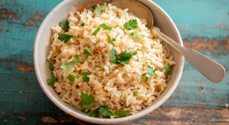 Un tazón de arroz integral esponjoso, adornado con perejil fresco, listo para ser disfrutado.