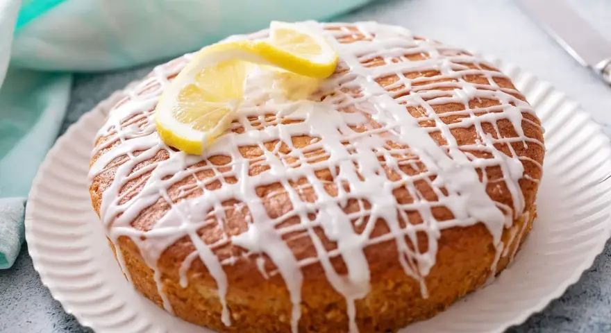 Pastel redondo con glaseado de limón y rodajas de limón fresco.
