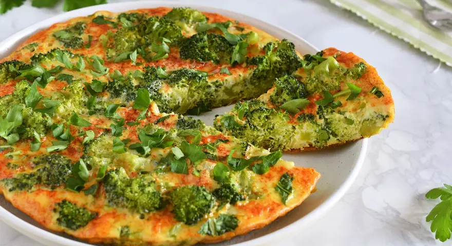 Deliciosa tortilla de brócoli, recién hecha y espolvoreada con perejil fresco. Un plato saludable y sabroso.