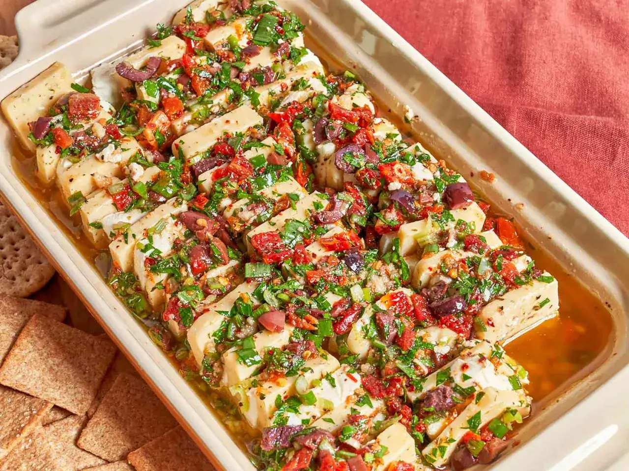 Queso feta horneado con tomates secos, aceitunas y hierbas. Una de las recetas saludables para comer, ideal para picar.