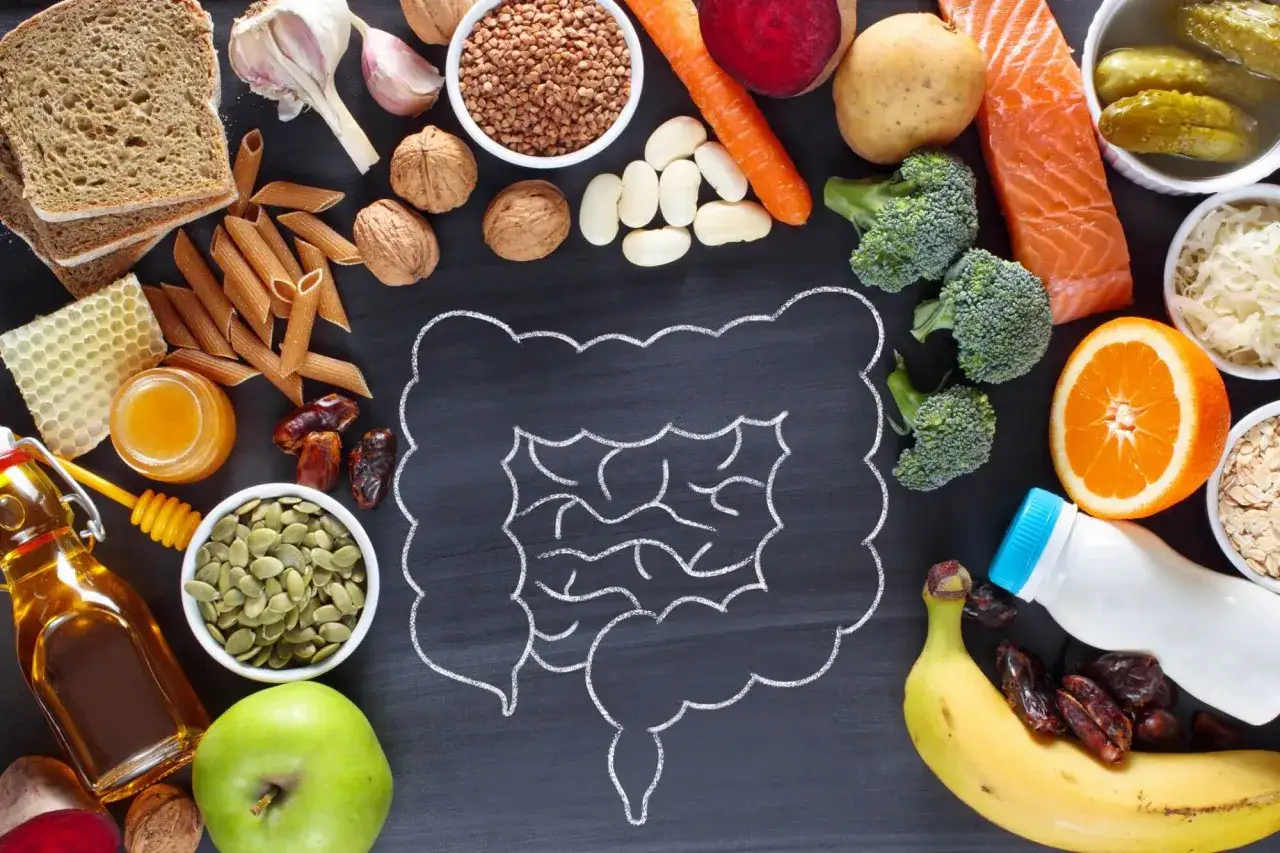 Alimentos variados como salm&oacute;n, br&oacute;coli, frutas y granos, rodeando un dibujo de intestinos, para una buena salud intestinal.