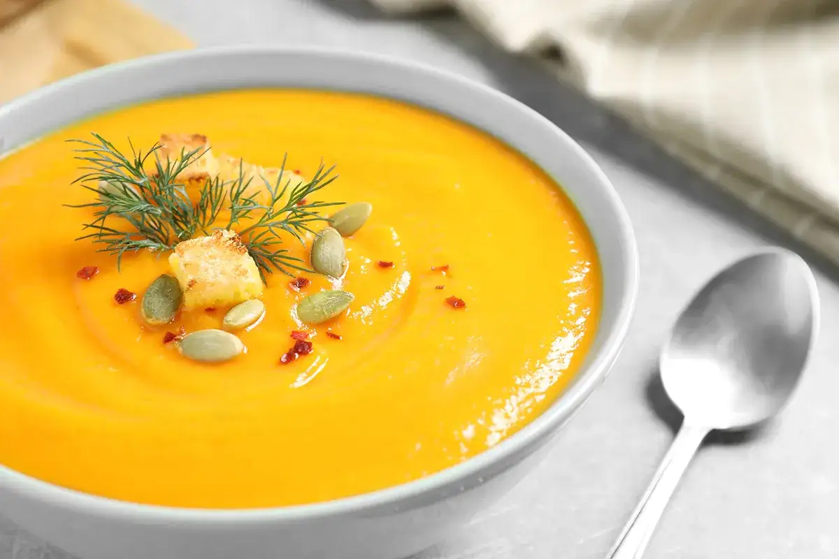 Crema de calabaza y jengibre, decorada con picatostes, pepitas y eneldo. Un plato reconfortante y lleno de sabor.
