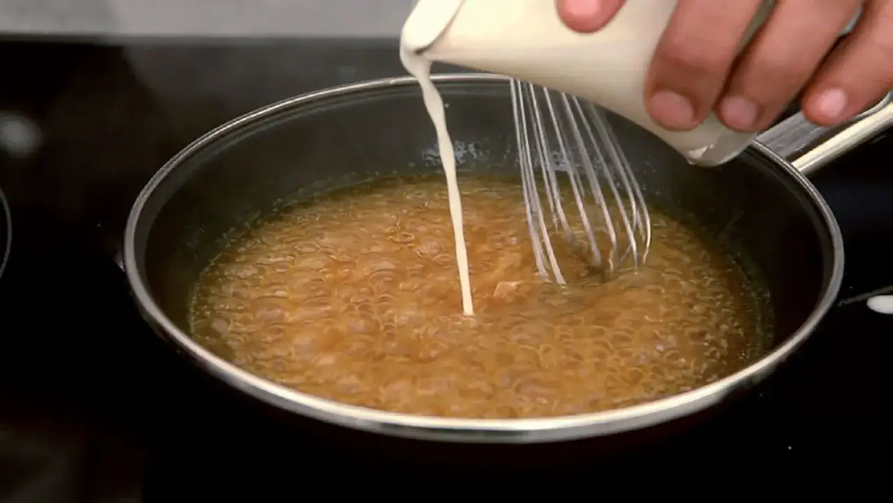 Se vierte crema en una sart&eacute;n con l&iacute;quido burbujeante, como si se preparara una salsa con maicena.